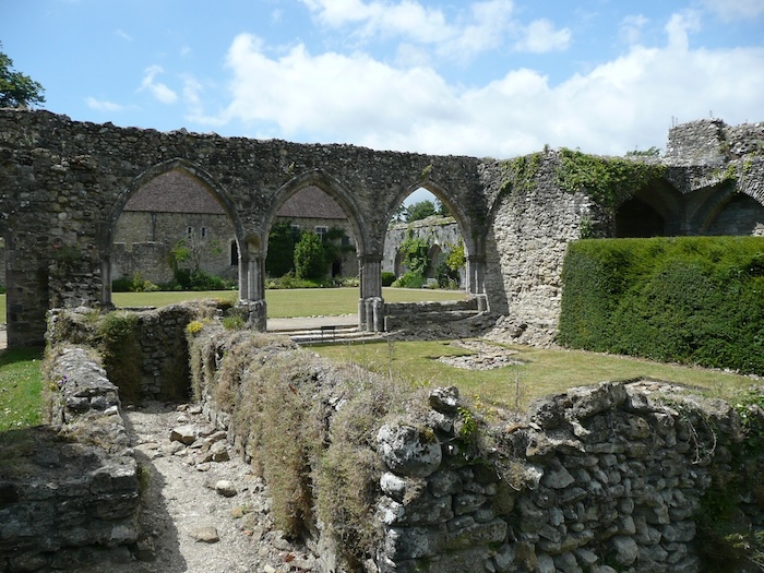 Ruins of Beaulieu Abbey, with stone walls in foreground and arches of a former cloister in the background. Photo by